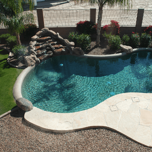 Picture of backyard with inground pool, landscaped bushes, gravel and artificial grass